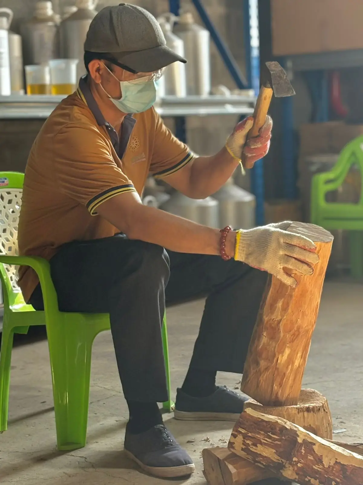 A Marigold craftsman desapping a sandalwood log by hand with a mallet